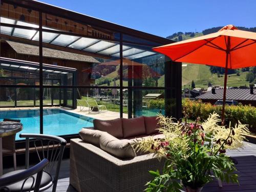 a patio with a couch and an umbrella next to a pool at Hotel Alpina in Morzine