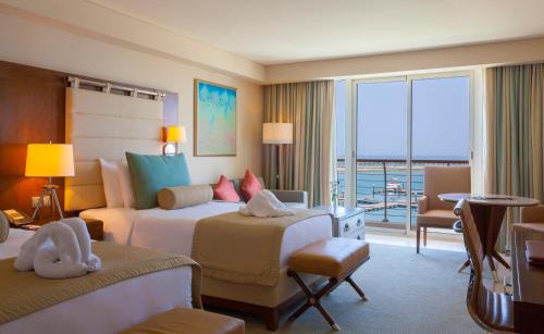 a hotel room with two beds and a balcony at Barceló Mussanah Resort, Sultanate of Oman in Mussanah
