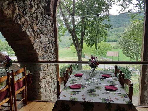una mesa en una habitación con una ventana grande en Hotel rural La soleia d'Oix, en Oix