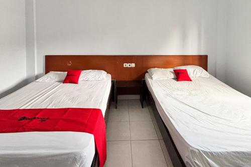 two beds with red pillows in a room at RedDoorz at Hotel Nuansa Indah Denpasar in Denpasar