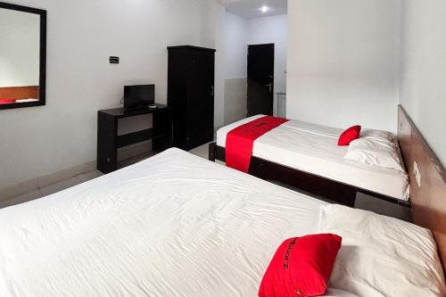 two beds in a room with red pillows at RedDoorz at Hotel Nuansa Indah Denpasar in Denpasar