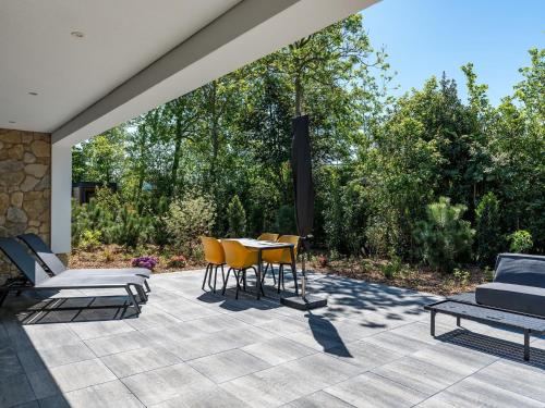a patio with yellow chairs and a table at Chalet in Texel near Forest & Beach in Den Burg