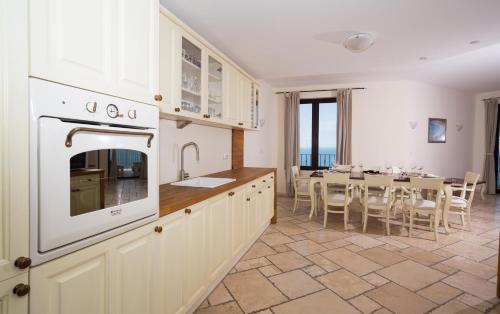 a kitchen with white cabinets and a dining room with a table at Kaliakria Resort in Topola