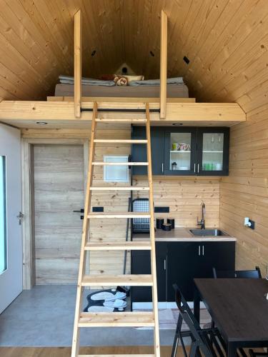 a loft bed in the kitchen of a tiny house at La - Mai Glamping in Žetale