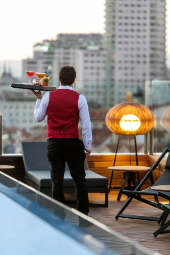 a man holding a tray of food on a rooftop at Palacio de los Duques Gran Meliá - The Leading Hotels of the World in Madrid