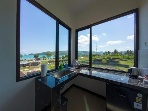 a kitchen with a counter with a sink and large windows at Mar Bella Beachfront in Kuta Lombok