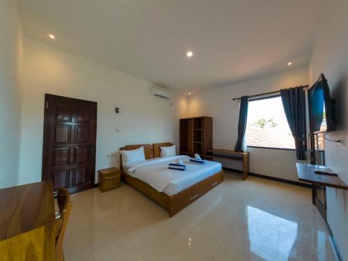 a bedroom with a bed and a flat screen tv at Mar Bella Beachfront in Kuta Lombok