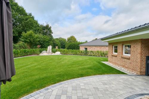 a garden with a lawn and a brick house at Kanalkajüte Wilhelm in Hanerau-Hademarschen