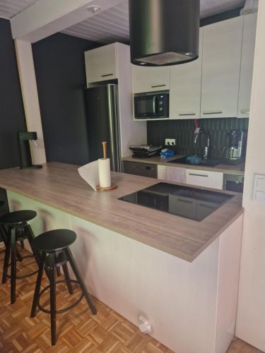 una cucina con mobili bianchi e un bancone con sgabelli di Compact beautiful apartment with sauna a Kuusamo