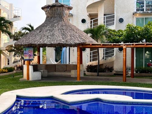 a gazebo and a swimming pool in front of a building at Departamento planta baja en la laguna in Acapulco