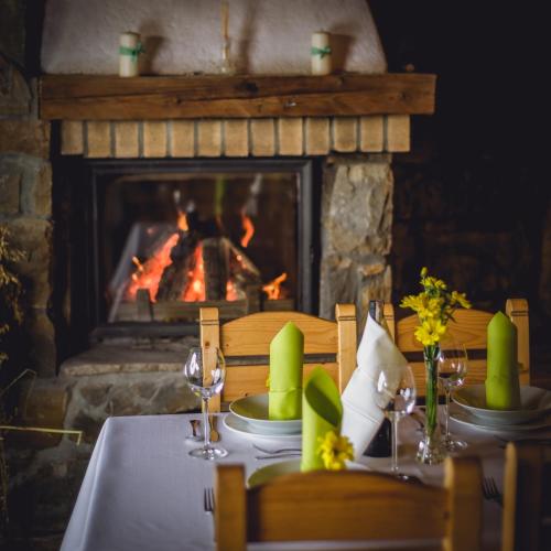 a table in front of a fireplace with a table set for a meal at Hotel Pod Wulkanem in Kluszkowce