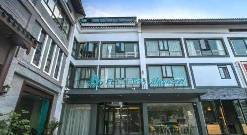 a building with a balcony with tables and chairs at Magnotel Hotel Suzhou Shiquan Street Wangshiyuan in Suzhou