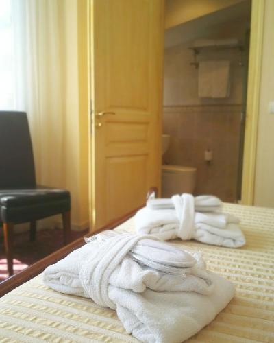 une pile de serviettes posée sur un lit dans l'établissement Hotel Alexandre III, à Cannes