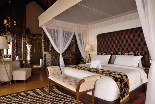 a bedroom with a large bed and a chair and a couch at Lake Manyara Kilimamoja Lodge in Mto wa Mbu