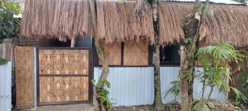 a house with a thatched roof and a gate at Silid Siargao in General Luna