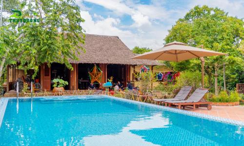 a swimming pool with chairs and an umbrella at Homestay Thùy Dương 2 in Cai Be