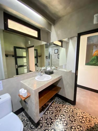 Un baño con lavabo y un espejo grande. en Saxy Stay Seminyak, en Seminyak
