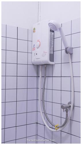 a shower in a bathroom with a white tiled wall at The Yard Sukhothai Old Town in Sukhothai