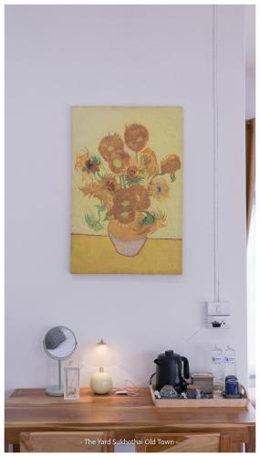 a painting of flowers in a pot on a wall at The Yard Sukhothai Old Town in Sukhothai