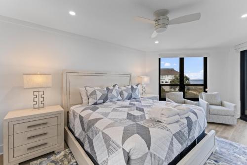 a white bedroom with a bed and a chair at Summer House 202 - 3BR Oceanfront Condo! View! in Isle of Palms