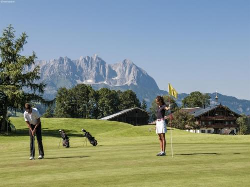 a couple of people playing golf on a golf course at Chalet in St Johann near Ski Slopes in Alpendorf