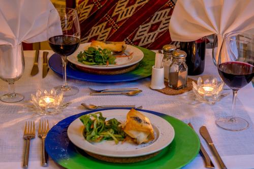 a table with two plates of food and glasses of wine at Hotel Los Castaños in Cartajima