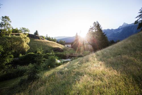 a grassy hill with the sun shining on it at Ferienwohnungen Ötztal in Sautens