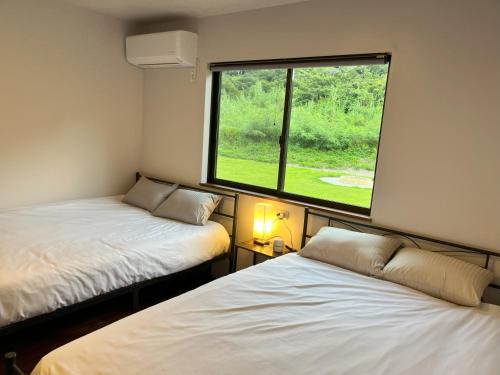 two beds in a room with a large window at ホシヤドリ hoshiyadori in Setouchi