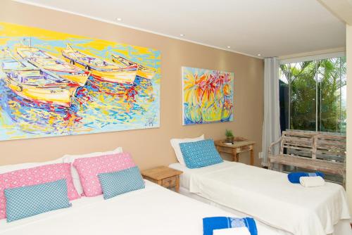 two beds in a room with a painting on the wall at Pousada La Dolce Vita in Búzios