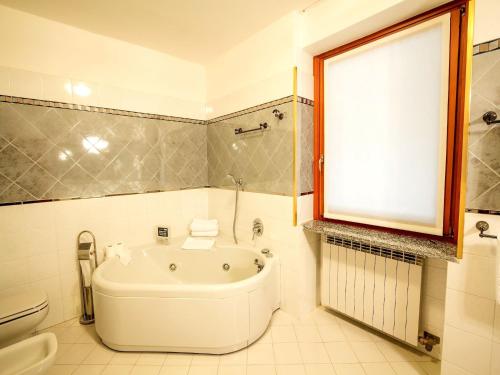 a bathroom with a tub and a toilet and a window at Lakeside Mansion with Pool in Artogne