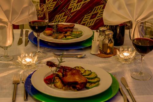 two plates of food on a table with glasses of wine at Hotel Los Castaños in Cartajima