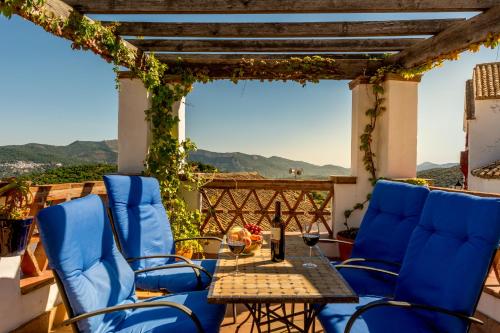 a patio with blue chairs and a table with a view at Hotel Los Castaños in Cartajima