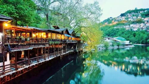 a restaurant next to a river with a building at Pansion River in Sarajevo