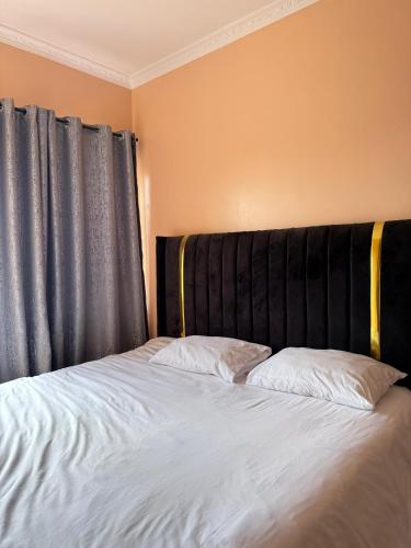 a bed with a black headboard and two pillows at Fairview apartments in Wote