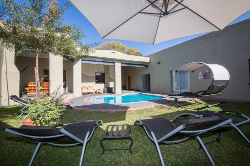 a yard with chairs and an umbrella and a pool at Foreva Wild in Klipdrift