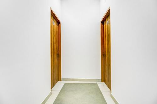 an empty corridor with wooden doors on a white wall at Collection O Kalpana Chawla Hospital Karnal in Karnal