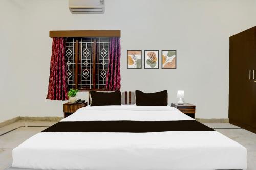 a bedroom with a large white bed and a window at Super Townhouse Madiwala Lake Park in Bengaluru