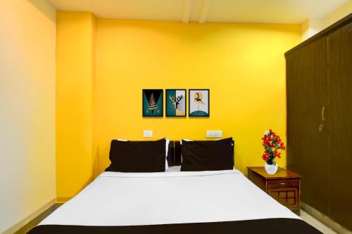 a bedroom with a white bed and a yellow wall at Super Collection O Gachibowli in Hyderabad