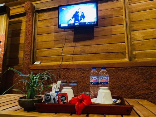 a television on a wall with a table with bottles of water at Sigiriya Ranasinghe Nature Villa & Cabana in Sigiriya
