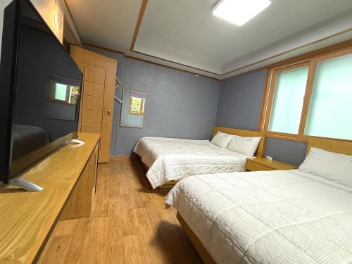 a hotel room with two beds and a flat screen tv at Gyeongju Bee House in Gyeongju