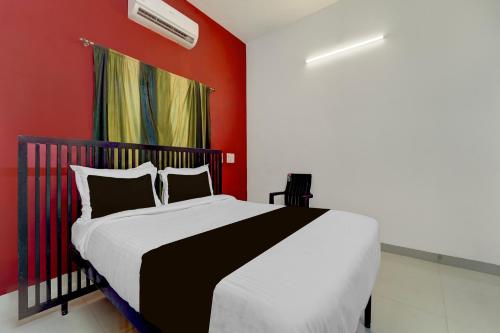 a bedroom with a bed with a red wall at Super Hotel O Auroville Bird Sanctuary Chennai Formerly Vanam Resort in Puducherry