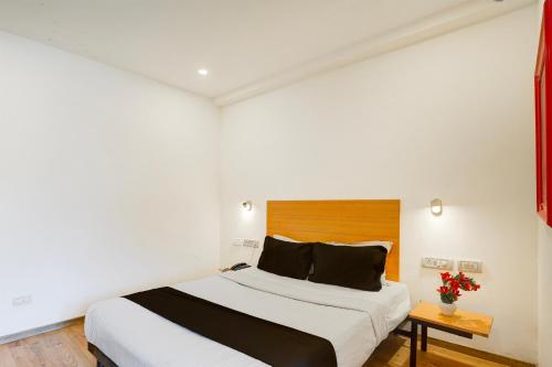 a bedroom with a large bed with a wooden headboard at Townhouse Sarjapur Road Formerly Hotel Ace in Bengaluru
