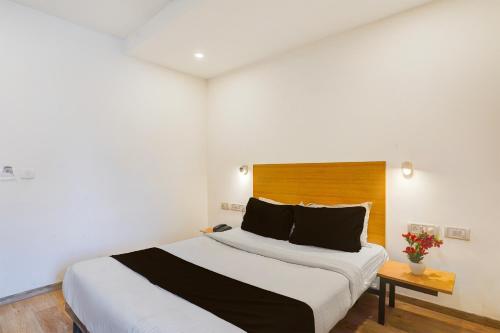 a bedroom with a large bed with a wooden headboard at Townhouse Sarjapur Road Formerly Hotel Ace in Bengaluru
