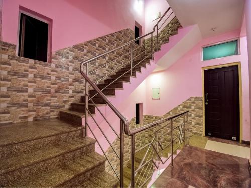 a staircase in a house with pink walls and a black door at Hotel O Kolkata Palace in Puri