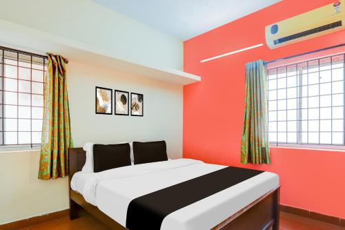 a bedroom with a bed with red walls and windows at Collection O DLF IT Park Ramapuram in Chennai