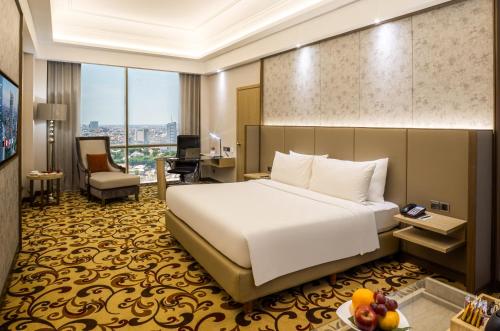 a hotel room with a large bed and a desk at Wyndham Surabaya in Surabaya