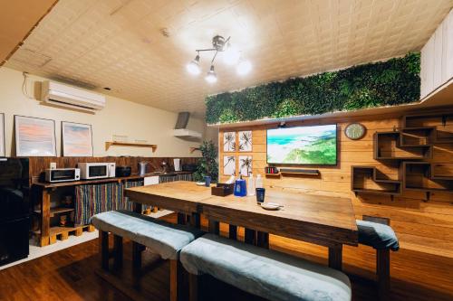 a dining room with a wooden table and plants on the wall at 全室個室 Private Stay Guesthouse Opuntia in Ishigaki Island