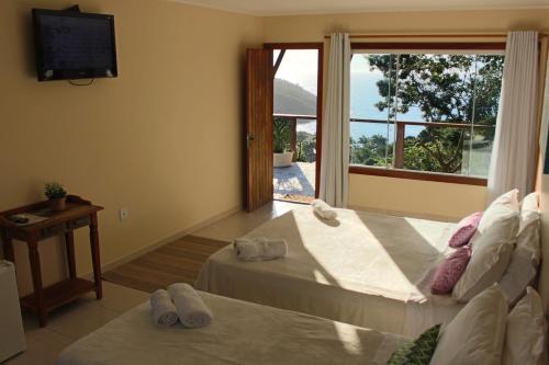 a bedroom with two beds and a tv and a window at Pousada La Dolce Vita in Búzios