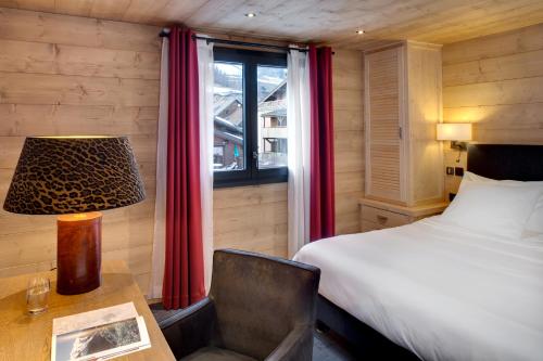 a bedroom with a bed and a desk and a window at Chalet-Hôtel La Marmotte, La Tapiaz & SPA, The Originals Relais in Les Gets