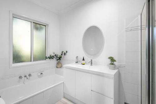 ヌーサヘッズにあるTropical Family Hideaway, Noosa Headsの洗面台と鏡のある白いバスルーム